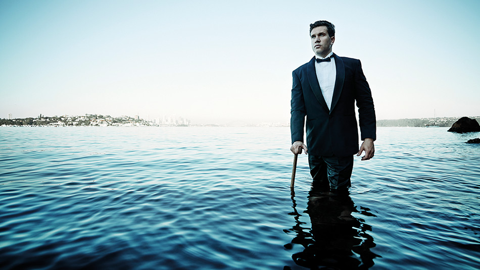A man in a suit walking in water with a walking stick